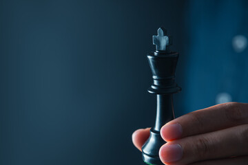 businessman hand holding black king of chess board ,team leader,  leadership and business strategy...