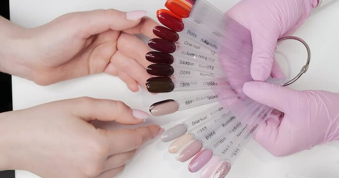 Client's choice of color for gel nail polish application in the salon. View from above, close up.