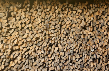 Firewood stacked near the wooden wall of old hut. Many chopped logs of firewood close up