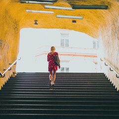 woman in red dress on the stairs of underground entrance