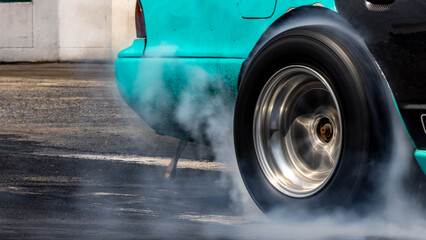 Car burnout wheels tire with white smoke,Car wheel burnout with smoke from the spinning tyre, Drag car wheel burns tires preparation for the race. © Darunrat