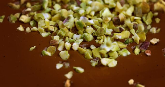 Super slow motion macro of bio organic almond nuts falling in creamy melted liquid dark cocoa chocolate with splashing dripping drops at 1000 fps.
