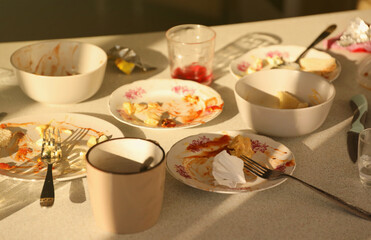 Empty dirty plates with spoons and forks on the table after meal. Banquet ending concept. Unwashed dishes ready to cleaning