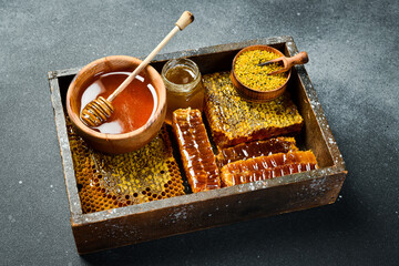 Set of honey, bee products and honeycomb honey. On a dark background. Top view. In a wooden box.