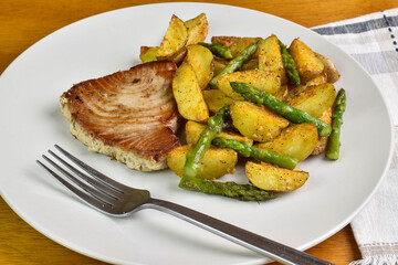tuna steak  served with  potato wedges and asparagus
