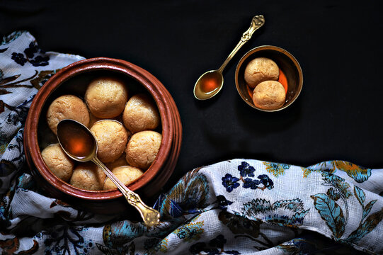 Mud bowl full with rasgulla or rasogolla with spoon on dark background. a food table top