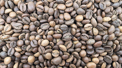 Roasted coffee beans can be used as a background. Top view of aromatic brown coffee beans scattered on the surface. Halves of dark brown coffee beans with a pleasant aroma.