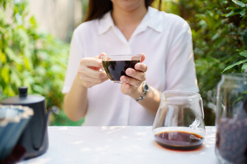 Happy Asian beautiful woman making a specialty coffee in morning at her backyard garden, woman brewing a coffee by dripping or pouring over a hot water.