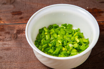 Finely chopped green onions in a white salad bowl on the table