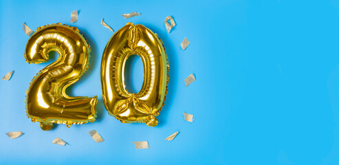 A balloon made of gold foil with the number twenty. A birthday or anniversary card with the inscription 20. the background color is blue.Anniversary celebration. The banner. a place to copy