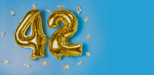 A balloon made of gold foil with the number forty-two. A birthday or anniversary card with the...