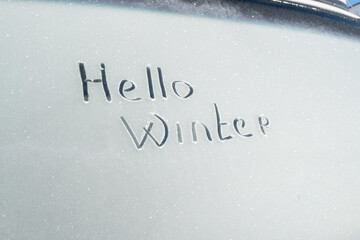 The inscription "Hello Winter" on a frozen car window.