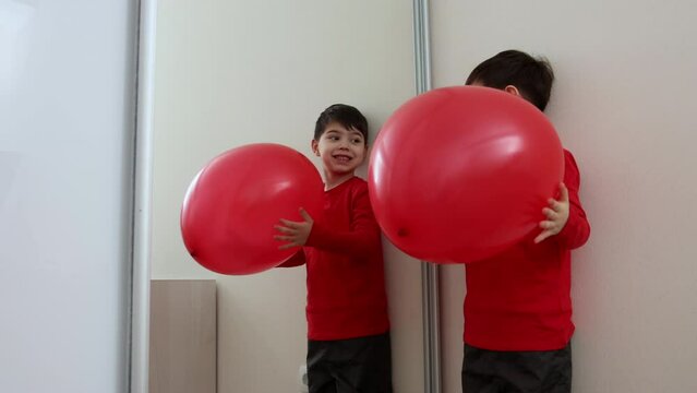 adorable preschooler boy kid with red balloon heart shaped against wall,smiling child hug heart or rising heart under blanket.valentines day.baby playing hitting ball, wardrobe with mirror.