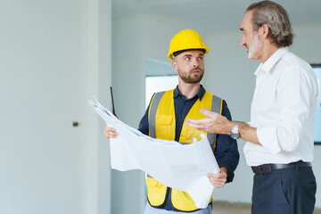 Portrait of caucasian male real estate customer talking - discussing with male building foreman - engineer about construction and interior works. Construction contractor talking with client.