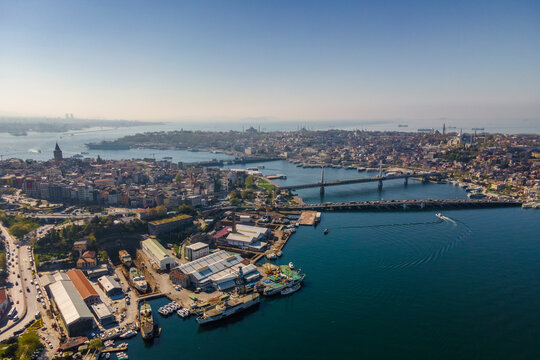 Aerial view of a boat sailing the Golden Horn waterway with Ataturk Bridge and Galata Bridge connecting the European Side of Istanbul downtown, Turkey.