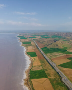 Aerial view of vehicles driving a scenic road along Lake Tuz (Tuz Golu), one of the largest hyper saline lake in the world, Central Anatolia Region, Ankara, Turkey.