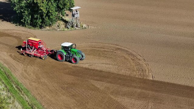 Aerial view of a thresher and a tractor, heavy duty machinery for agricultural farm working harvesting the grain in a field, Brandenburg, Germany.