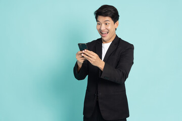 Happy Asian businessman typing or using mobile phone isolated on green background