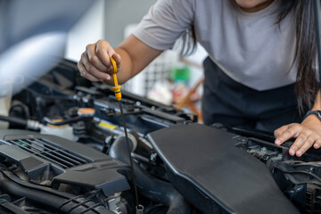 A young woman checking the car engine oil by herself