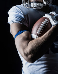 Close up studio photo of an American Football player holding tightly onto a football. Good generic American Football photo