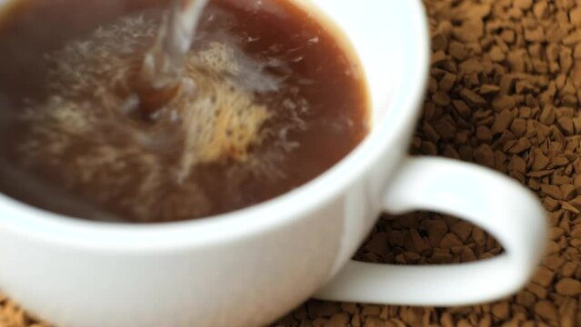 Brewing instant coffee, pouring boiling water over the granules. Delicious aromatic granulated coffee