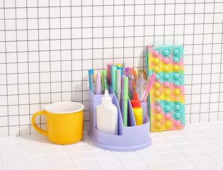 Stationery set on the desktop. A brightly colored pencil case, a yellow tea or coffee cup.