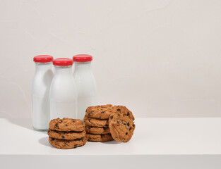 Glass bottles of milk and cookies with chocolate chunks. Copy space for text.