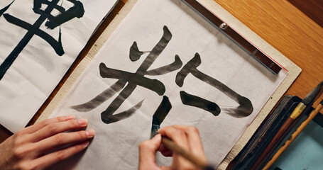 Hands writing, brush and Asian font for art and script, calligraphy with closeup of alphabet....