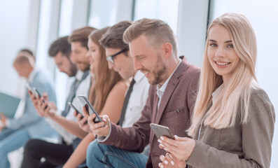 young business people with smartphones sitting in office corridor.
