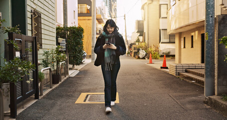Japanese woman, phone and texting in city, street and typing for contact, email and notification on...