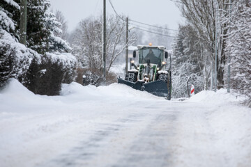 Tractor clears snow on road after heavy snowfall, road maintenance in winter season, harsh weather