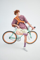 studio portrait of a red-haired young stylish sporty man with a bicycle