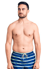 Young handsome man wearing swimwear smiling looking to the side and staring away thinking.