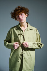 studio portrait of a young man with red curly hair wearing a green shirt with ties, green clothes