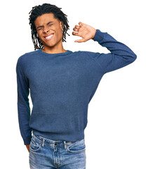 Young african american man wearing casual winter sweater stretching back, tired and relaxed, sleepy...