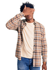 Handsome african american man with afro hair wearing casual clothes and glasses covering eyes with hand, looking serious and sad. sightless, hiding and rejection concept