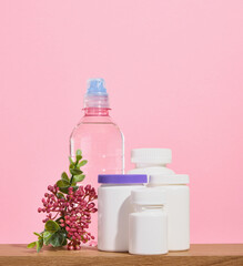 A large number of medical jars with pills and capsules and a plastic water bottle on a wooden table. A group of medicine pills.
