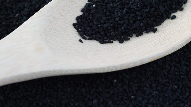 black cumin seeds on a wooden spoon rotation.. macro of black cumin seeds. black cumin harvest, use in cooking and medicine