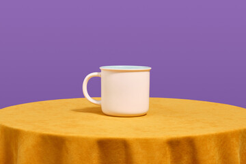 A white cup for various drinks stands on a bright yellow table. Dishes assortment.