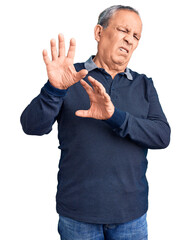 Senior handsome man wearing casual polo disgusted expression, displeased and fearful doing disgust...