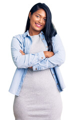 Hispanic woman with long hair wearing casual denim jacket happy face smiling with crossed arms...