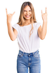 Beautiful caucasian woman with blonde hair wearing casual white tshirt shouting with crazy expression doing rock symbol with hands up. music star. heavy concept.