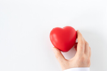 Female doctor holding red heart in hand isolated on white background. Top view. Copy space. Organ donation, healthcare, love, and medical support concept.