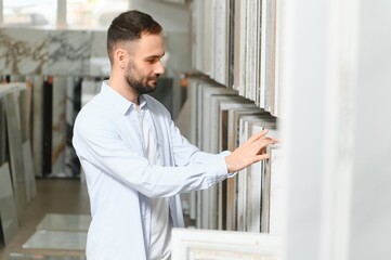 Fototapeta premium man choosing ceramic tiles and utensils for his home bathroom