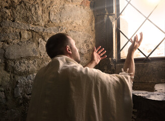 Ancient man praying at the window