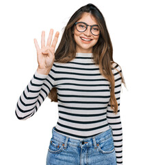 Obraz na płótnie Canvas Young beautiful teen girl wearing casual clothes and glasses showing and pointing up with fingers number four while smiling confident and happy.