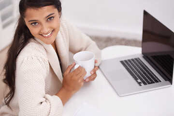 Portrait, home and woman with a laptop, coffee and smile in a living room, internet and connection. Face, person on a couch or girl in a lounge, technology and computer with daily news or digital app