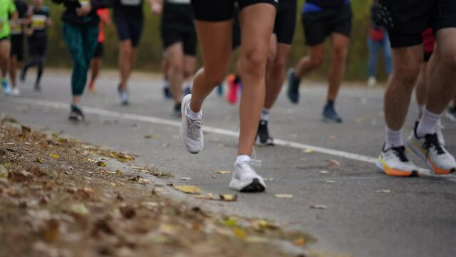 Focused on runners' feet, this image captures dynamic energy of marathon in progress amid the fallen leaves of autumn