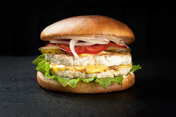 Cheeseburger on a black wooden background looks appetizing