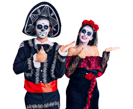 Young couple wearing mexican day of the dead costume over background showing palm hand and doing ok gesture with thumbs up, smiling happy and cheerful